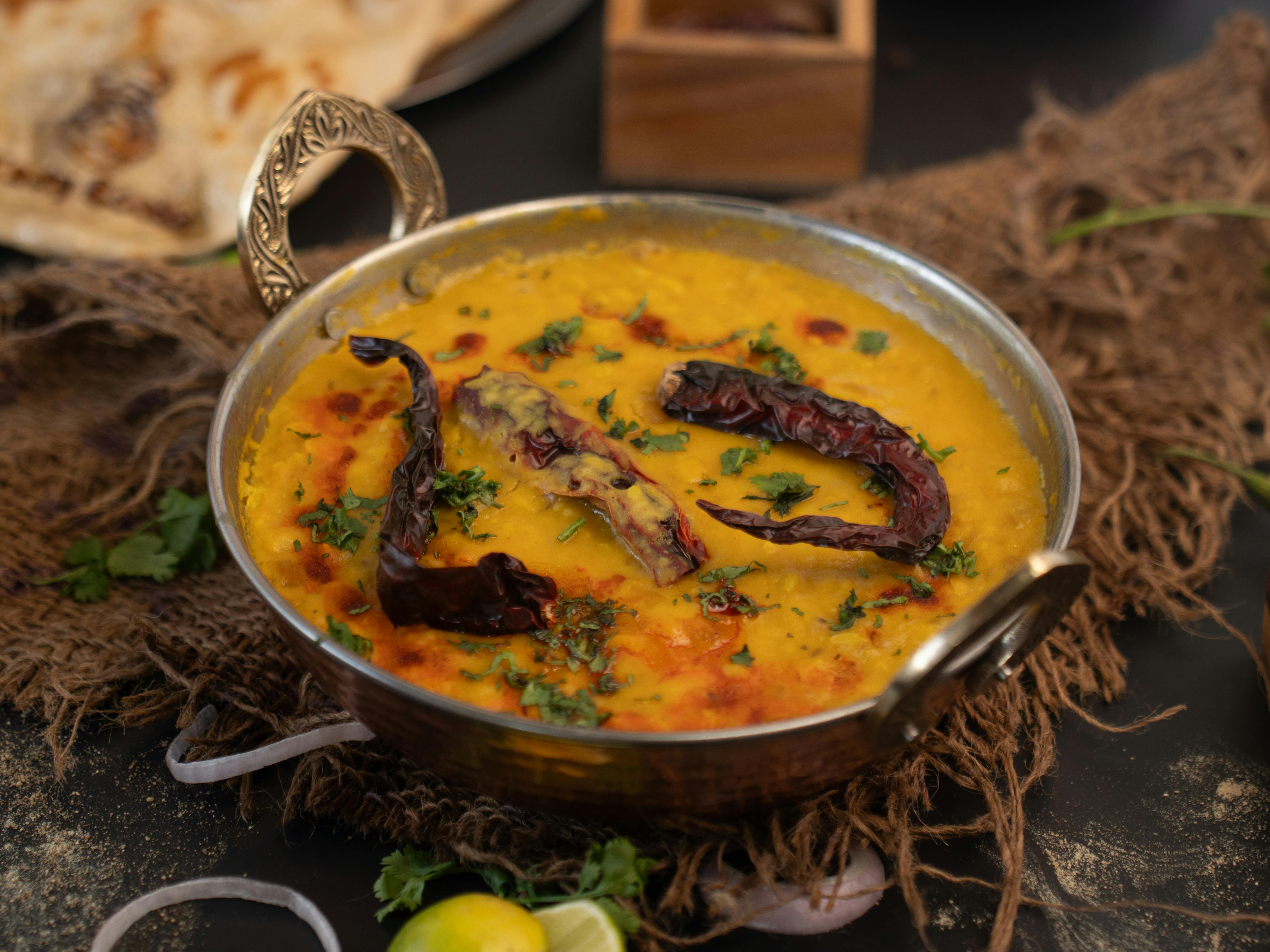 Delicious Indian lentil curry garnished with dried chilies and cilantro in an ornate bowl.