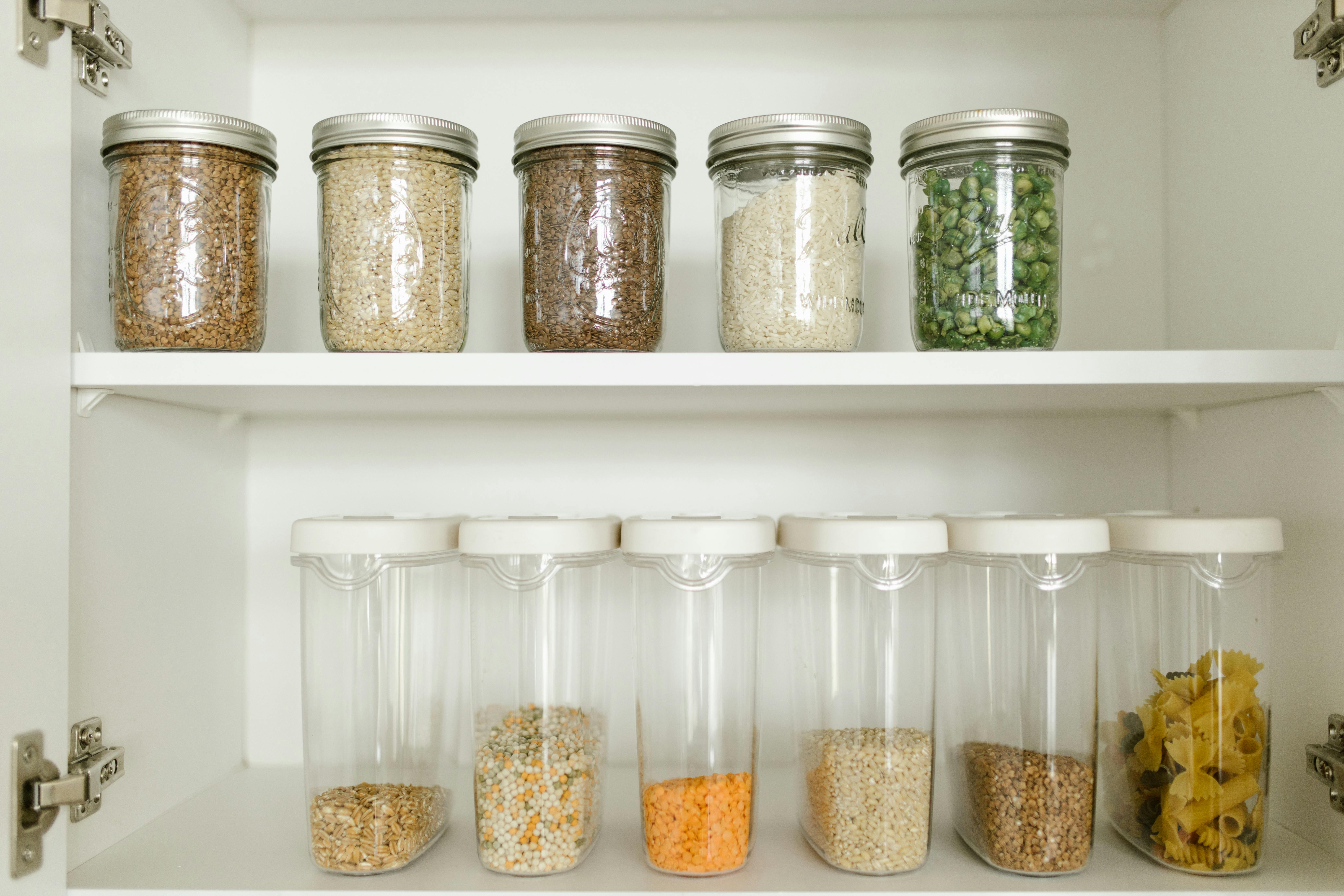 Neatly arranged pantry showcasing grains in glass jars and dry goods in plastic containers.